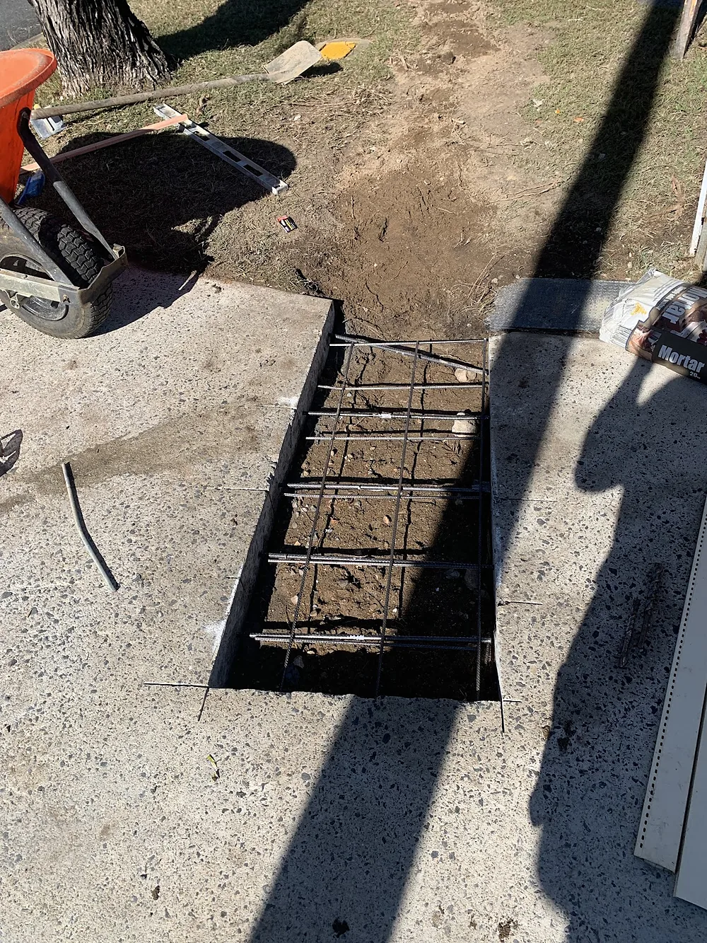 Cut section of concrete path with steel reinforcing mesh set ready for a pour