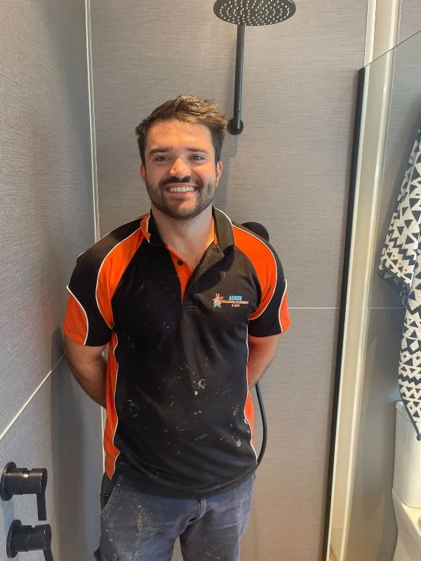 Linken, qualified plumber and gas fitter, smiling in a finished bathroom